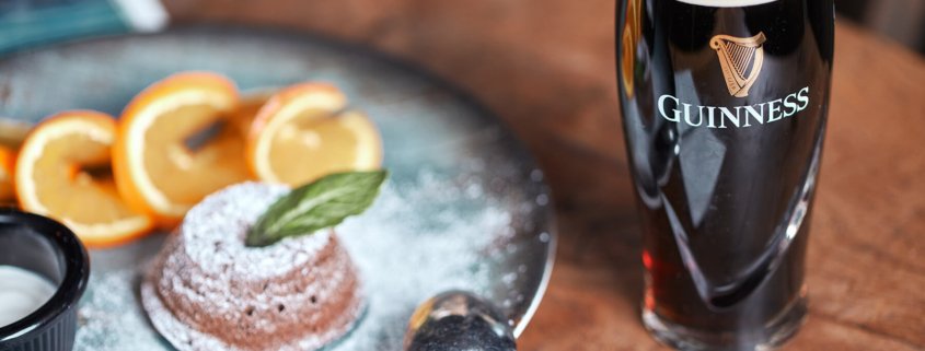 Dolce al cioccolato preparata con la birra Guinness accanto una pinta di stout irlandese.